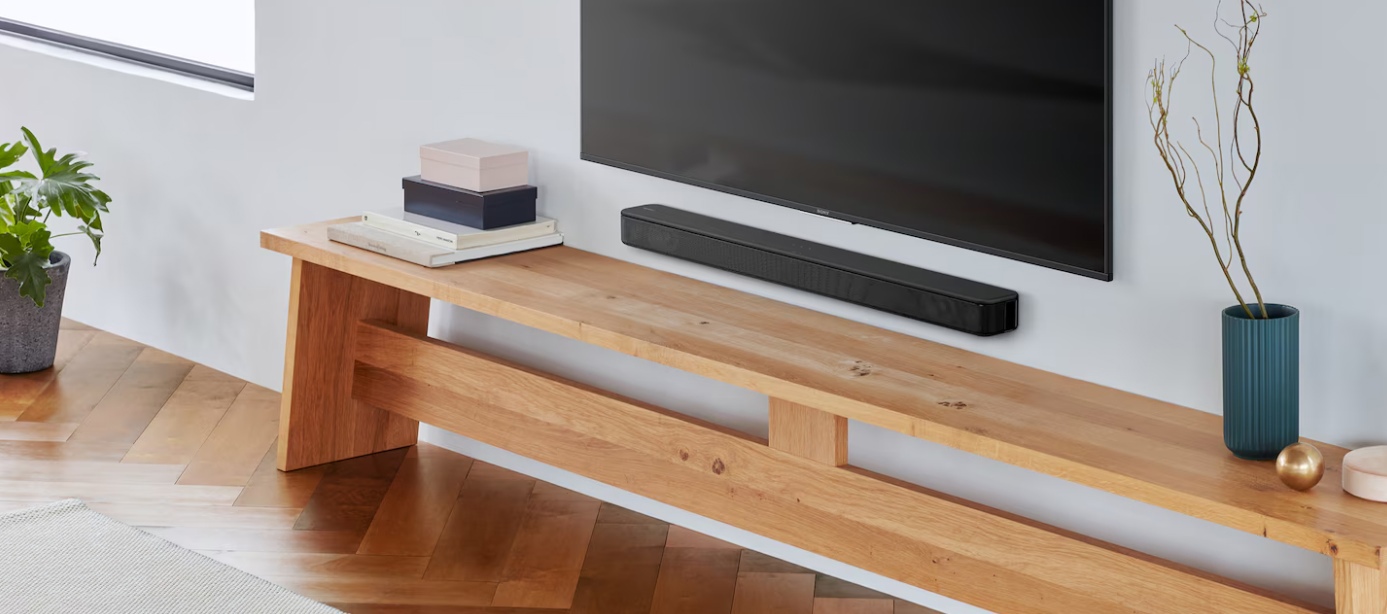 Sony HT-S100F под телевизором на стене, интерьерный вид с деревянной подставкой