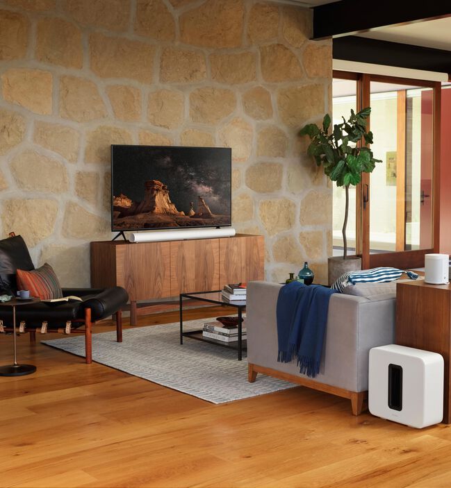 Sonos Arc Black под телевизором на фоне каменной стены — демонстрация в стильном интерьере